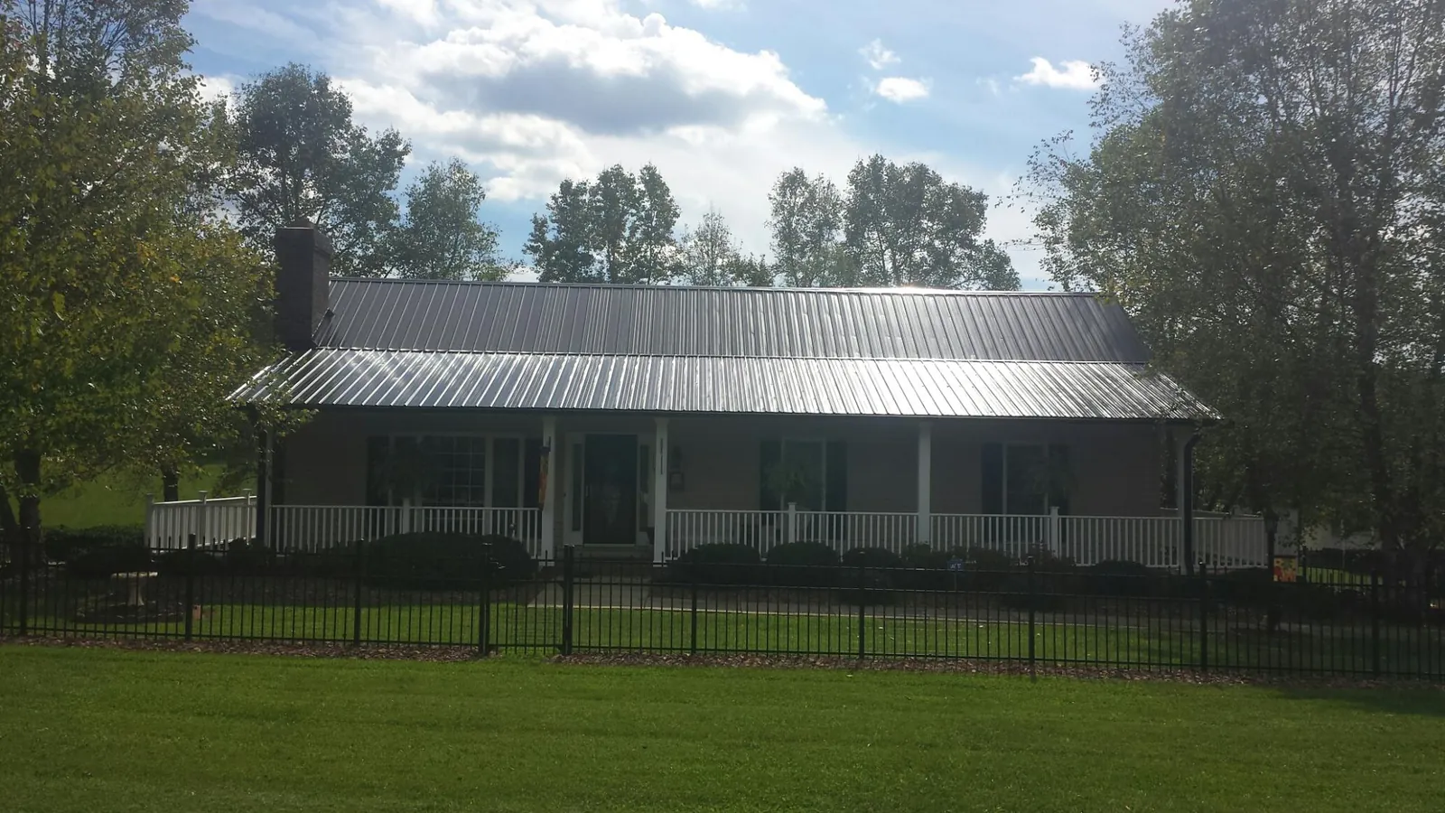 Gray metal roof on a brick ranch with a full width front porch — Gutter Guard Installation work by our crew in Parrish